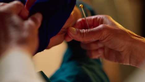 Close-Up-Studio-Shot-Of-Senior-Sikh-Man-Helping-Younger-Sikh-Man-To-Tie-Fabric-For-Turban-Against-Plain-Background-Shot-In-Real-Time-1